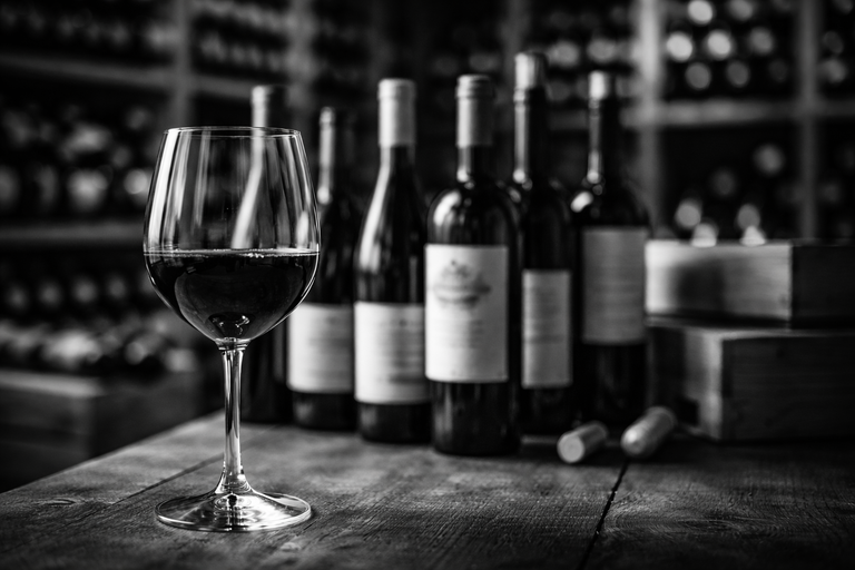 Copa de vino en primer plano con botellas al fondo en un almacén, ilustrando un caso de éxito de PR para un ecommerce de vino